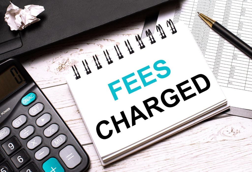 a working business desk with a calculator on it. The focus is on a notepad showing fees being charged.